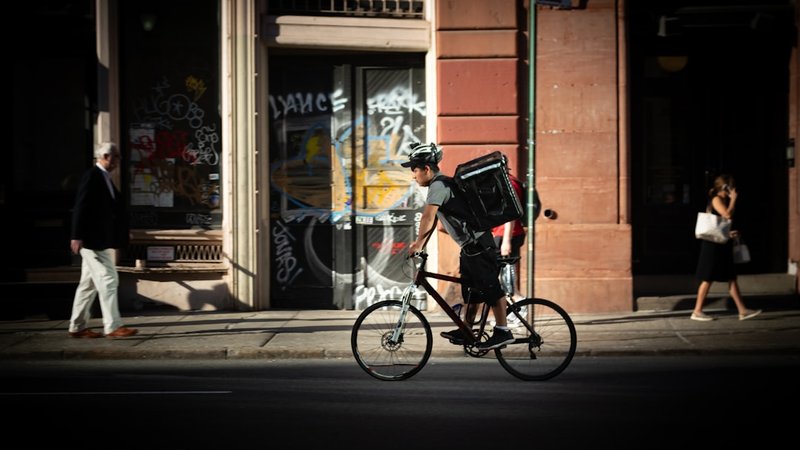 配達バッグを背負い自転車で街を走る配達員