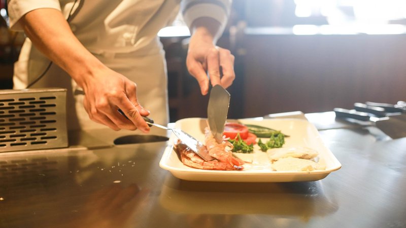 飲食店の厨房で調理・盛り付けするイメージ